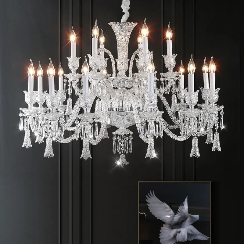 Kerzen-Kronleuchter aus klarem Glas mit Kristallbehang, eingeschaltet, vor dunkler Wand