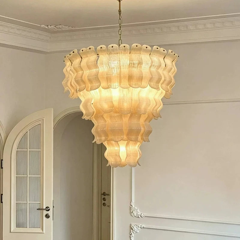 Kronleuchter aus gewelltem Glas, eingeschaltet, in einem hellen Raum mit Stuck